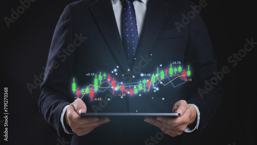 A man in a suit holding a tablet with a stock exchange graph showing a stock market trend analysis and forecast. Financial investment and stock trading concept.