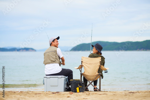 浜辺で座って釣りをする男女 photo