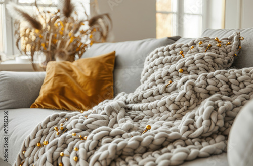 Sofa with a white and gold knitted blanket, grey sofa in a light gray room interior, golden accessories, modern home decor in the style of modern home decor