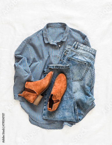 Women's casual comfortable clothes - blue cotton plaid shirt, blue jeans, chelsea boots on a light background, top view