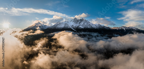 Tatranska Lomnica  Slovakia - Aerial panoramic view of the snowy peaks of the High Tatras above the clouds with the Lomnicky Peak  the second highest peak of the High Tatras mountains at sunset