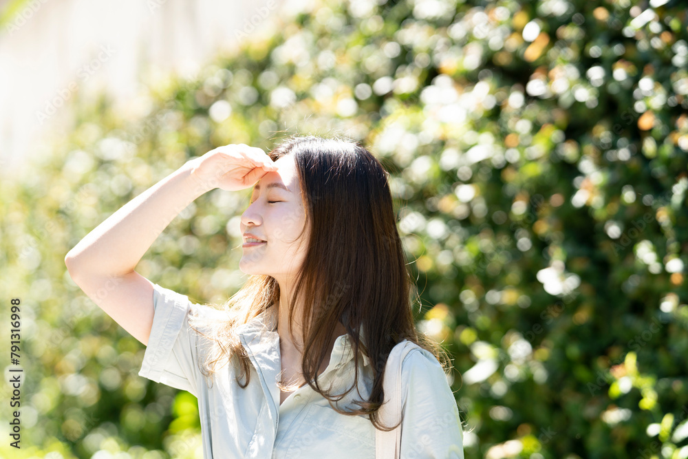 日差しを遮って眩しそうな顔をしている女性