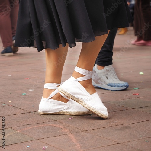 Woman wearing white traditional shoes dancing the sardana, a Catalan folk dance. Closeup view of espardenyes. Square poster