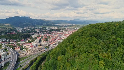 Cityscape of Banska Bystrica (Slovakia) behind Urpin mountain in summer. Aerial drone footage. City behind beautiful green forest. photo