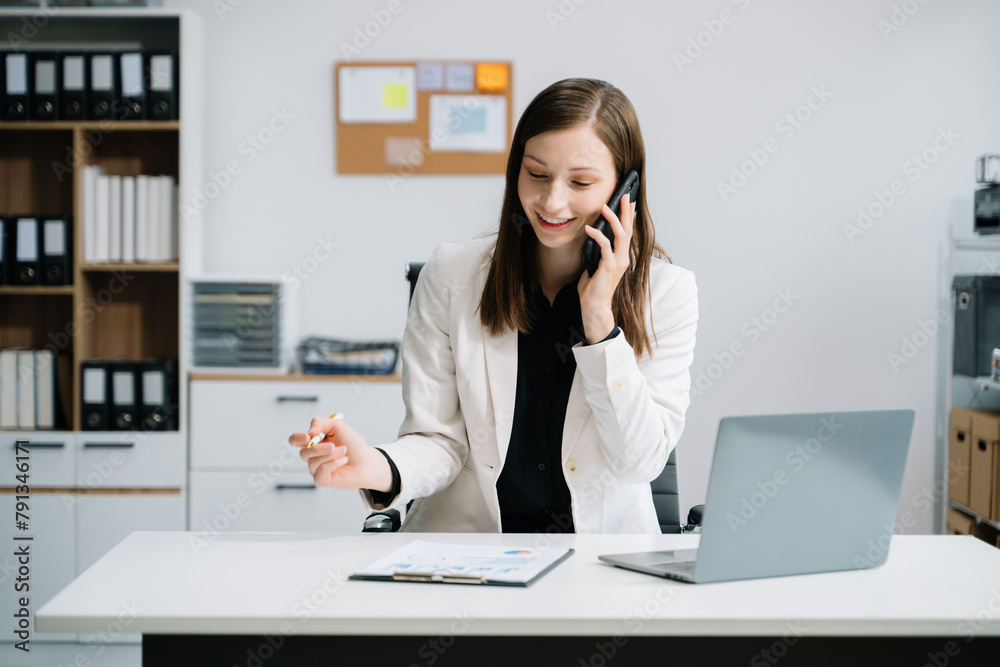 Young woman using laptop and tablet while sitting at her working place. Concentrated at work.. Young woman using laptop and tablet while sitting at her working place. Concentrated at work..