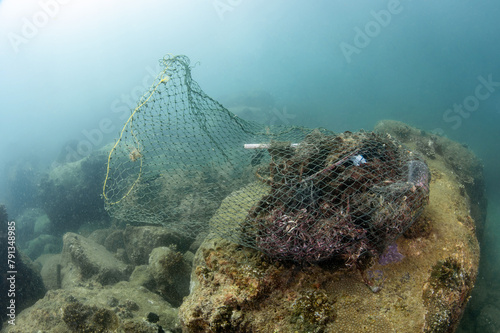 Clean up the ocean by collecting waste. Abandoned debris fishing net or ghost net and plastic garbages in the sea. Save the ocean and underwater world from trash pollution. Environmental conservation