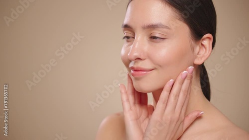 Beautiful Young Woman Touches Her Perfect Face. Natural Cosmetic Skincare Products. Woman demonstrate moisturizing facial care. Elevating Close-up Portrait with Isolated Background. Slow motion