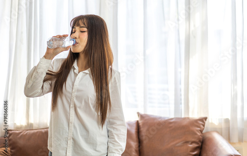 Portrait asian beauty body slim woman drinking water from a bottle while relax and feeling fresh   refresh drink  wellness  diet  healthcare  mineral at home.Healthy liquid lifestyle concept