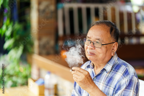 An elderly man was smoking tobacco that was emitting smoke. The concept of harming health.