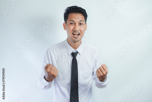 Young Asian business man showing happy excited expression with clenched fist photo