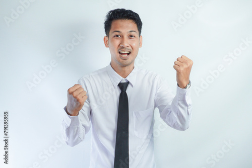 Young Asian business man showing happy excited expression with clenched fist photo