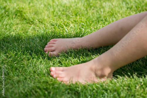 Fototapeta Naklejka Na Ścianę i Meble -  Bare feet of a child on meadow in green grass (lawn) in summer