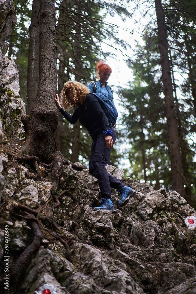 Tourist women with backpacks hiking on a trail in the mountains Tourist women with backpacks hiking on a trail in the mountains