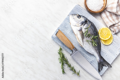 Photography Fresh sea bream fish on cutting board on kitchen table. Top view.