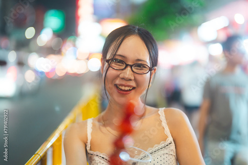 Young adult asian foodie woman eating chinese dessert Tanghulu at china town asia street food © dodotone