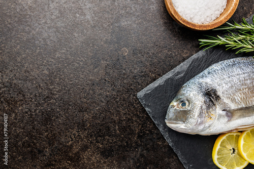 Fresh sea bream fish on cutting board on kitchen table. Top view. photo