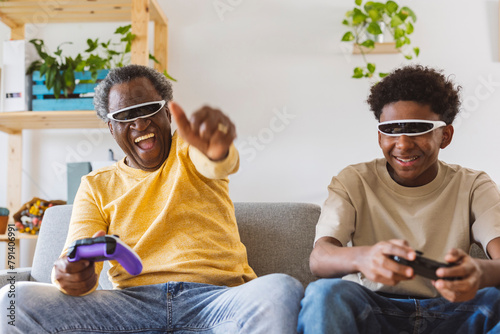 Cheerful grandfather and grandson playing video game at home photo