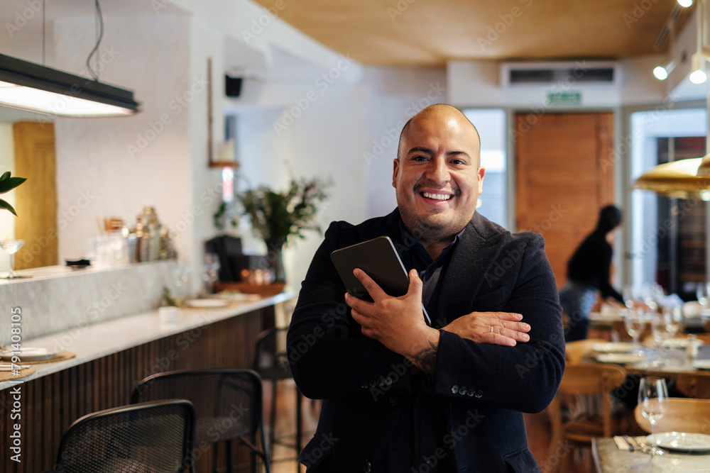 Smiling restaurant owner standing with tablet PC Smiling restaurant owner standing with tablet PC