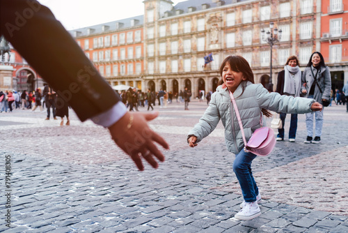 Cheerful girl running towards father at town square photo
