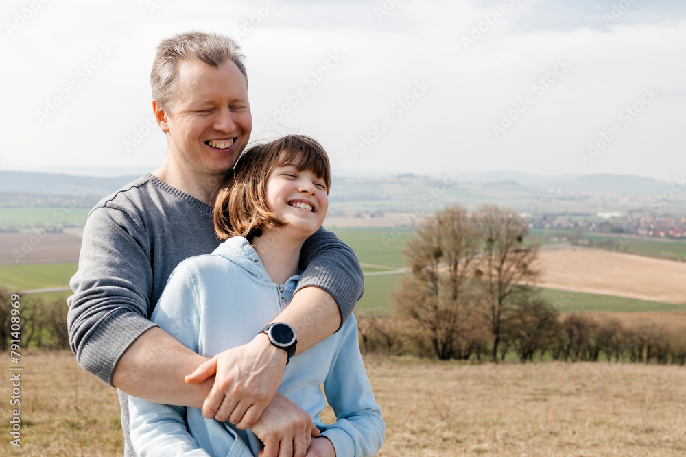 Happy man with arms around daughter standing on hill