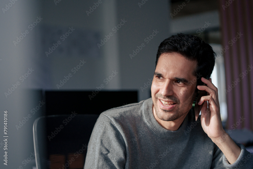 Happy businessman talking on mobile phone in office Happy businessman talking on mobile phone in office