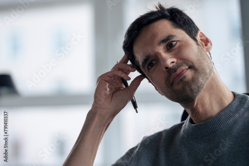 Contemplative mature businessman with pen in office photo