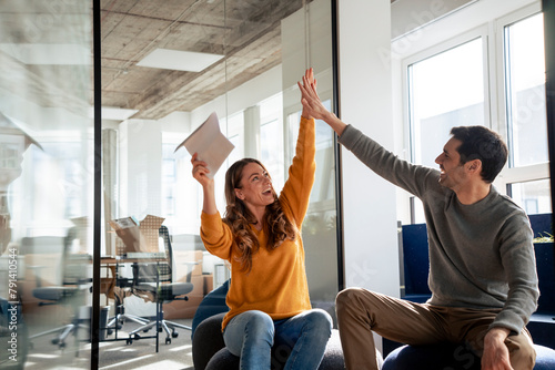 Successful business people giving high-five to each other in office photo