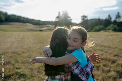 Young girl best friends spending time in nature, during sunset. Girls on walk, embracing.