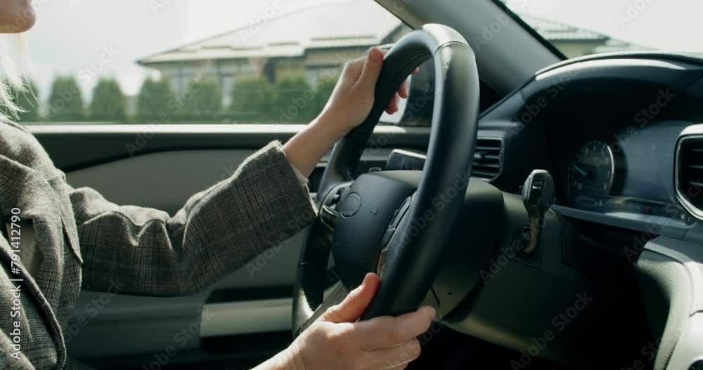 A business woman drives a car around the city on a sunny day, close-up of her hands on the steering wheel, an unrecognizable person A business woman drives a car around the city on a sunny day, close-up of her hands on the steering wheel, an unrecognizable person