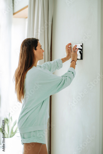 Woman using tablet PC mounted on wall at home