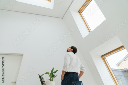 Businessman looking at skylight in minimalist office photo