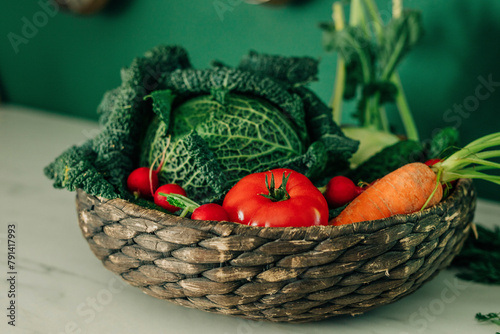 Various fresh vegetables in wicker basket on table in kitchen photo