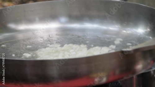 The process of frying onions in oil in a large skillet, cooking the ravioli.