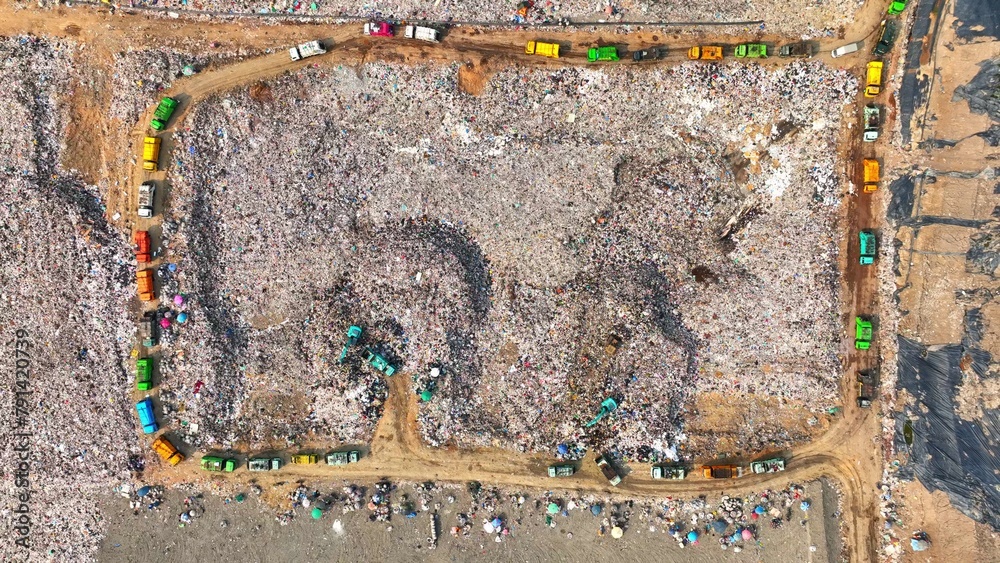 An aerial view over a colossal landfill, a patchwork of vivid waste