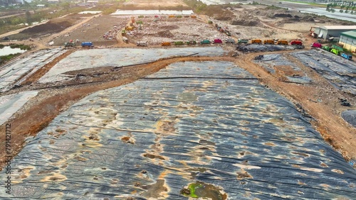 A sprawling landfill concealed under expansive black plastic sheets, a testament from above to containment and environmental stewardship. Landfill background. Aerial view.
 photo