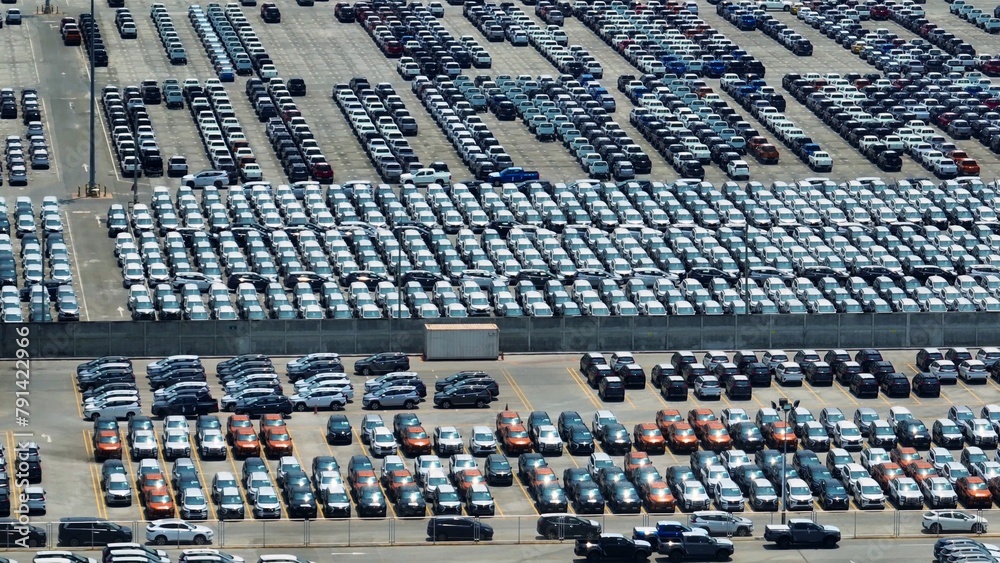 Obraz premium A bird's-eye perspective captures a vast parking lot, meticulously organized rows of vehicles creating a mesmerizing pattern of order and functionality. 