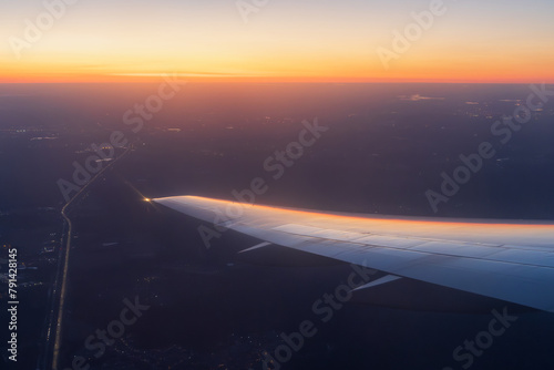 Sunset view from a flying airplane. Beautiful evening aerial landscape. View of an airplane wing. Travel and aviation tourism. Flight on a passenger airliner.