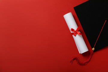 Graduate hat with diploma on red background.