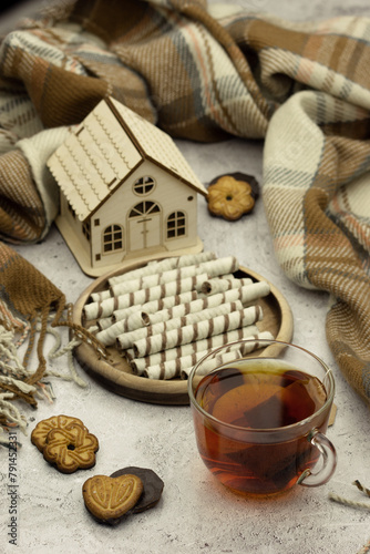 Tea, dessert and a house for a cozy atmosphere. Poster for interior. Sweets for tea on the table. A warm blanket as a symbol of comfort.