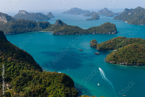 Boats navigate the serene blue waters among lush green islands under a clear sky. Koh Samui Island, Thailand