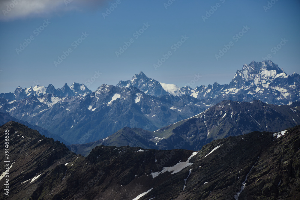 Scenic view of towering snow-covered mountains against a serene blue sky backdrop