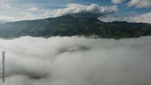 Aerial view of Rumiñahui volcano through thick white clouds. Discovering an Ecuadorian landmark on a sunny morning from a drone. Machachi city area, Pichicnha province photo