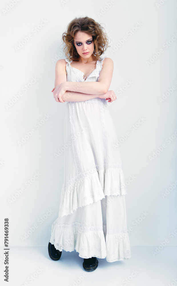 Portrait of attractive strange girl. Beautiful odd young woman in white dress standing at wall