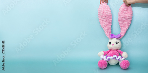 Bunny. Long ears. Hobby crochet. Handmade. Amigurumi. Pink knitted rabbit. Soft toy.  Pink and blue color. Crocheting of soft toys
