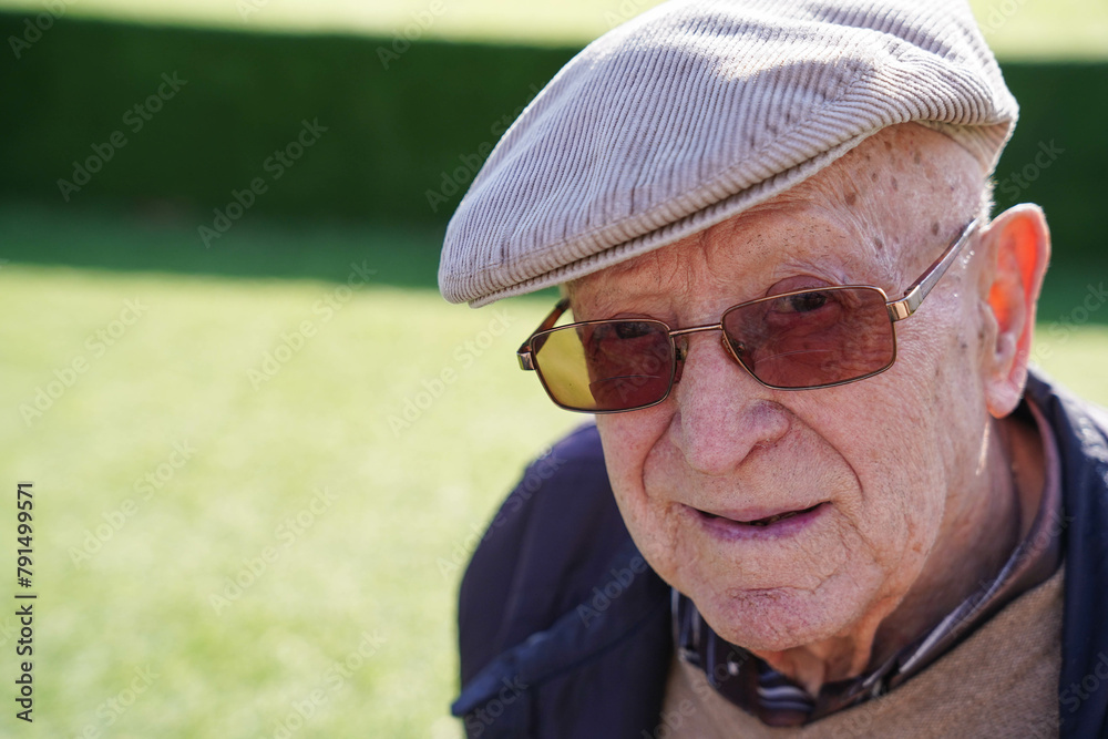 Close-up portrait of an old man smiling at camera in a park