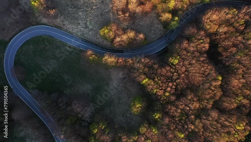 Zenith aerial view of an isolated road in the mountain forest in the park appennino tosco emiliano with a car traveling alone. Concept of driving the car in the forest with autumn foliage photo