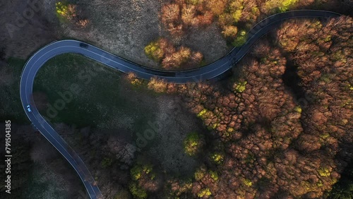 Zenith aerial view of an isolated road in the mountain forest in the park appennino tosco emiliano with a car traveling alone. Concept of driving the car in the forest with autumn foliage photo