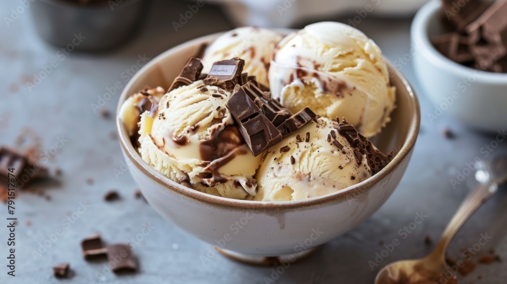 Bowl of vanilla ice cream with chocolate shavings and chunks on a table