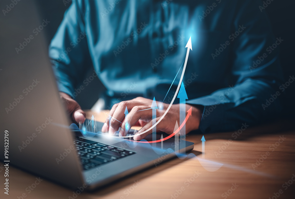Obraz premium chart, global, graph, index, invest, marketing, report, strategy, growth, statistics. A man is typing on a laptop with a graph of a rising arrow on the screen. Concept of progress and growth.