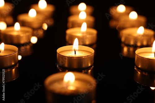 Burning candles on mirror surface in darkness  closeup